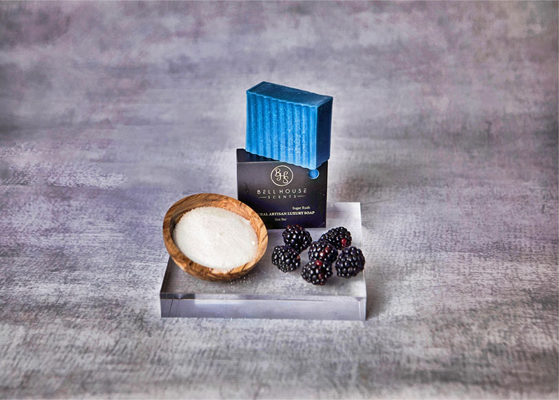 Blue Artisan Soap next to a small wooden bowl of blackberries and sugar.
